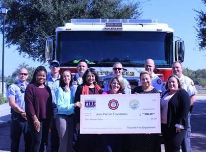 group in front of fire truck holding check